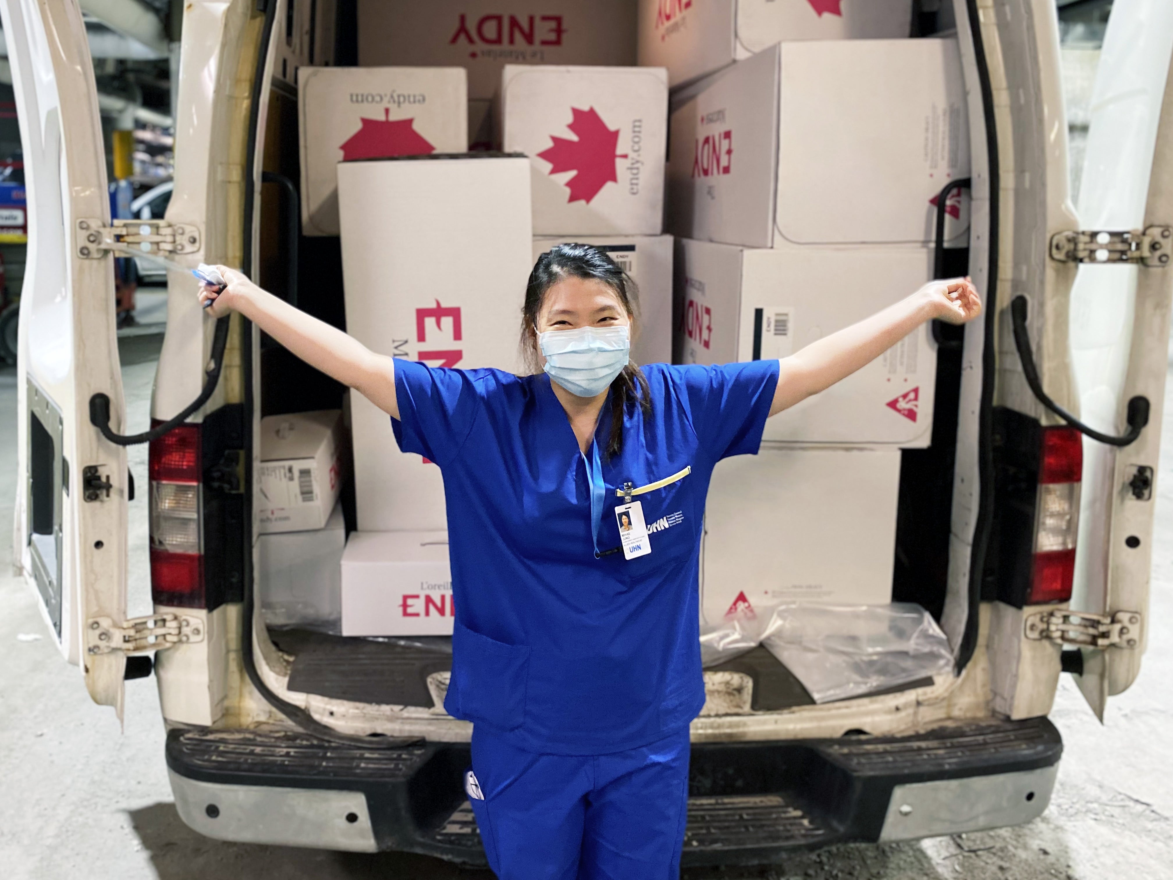 Un travailleur de la santé du Réseau universitaire de santé se tient devant un véhicule rempli de boîtes à matelas Endy.